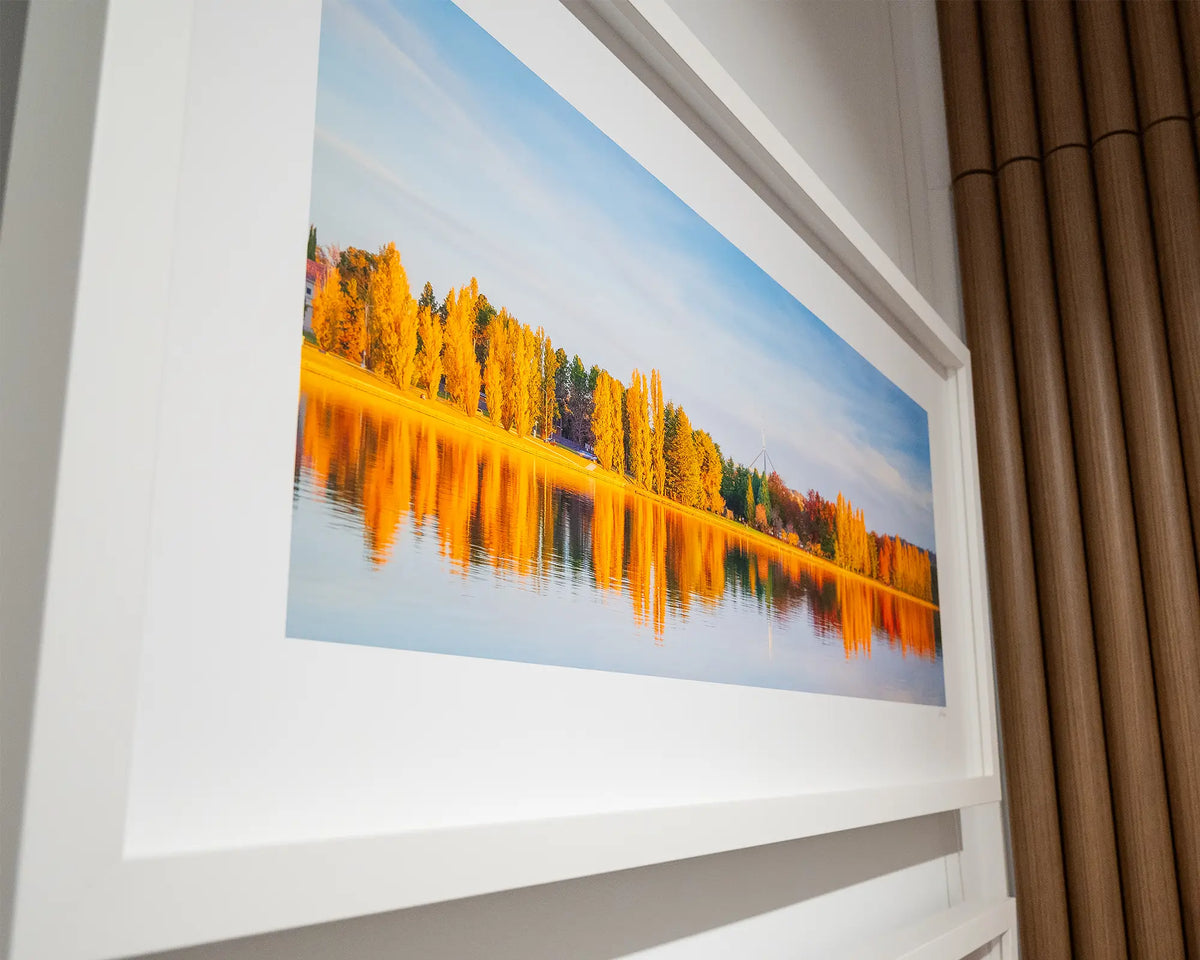 Changing Seasons. Wall art print with white frame of autumn trees at sunset beside Lake Burley Griffin, side view.