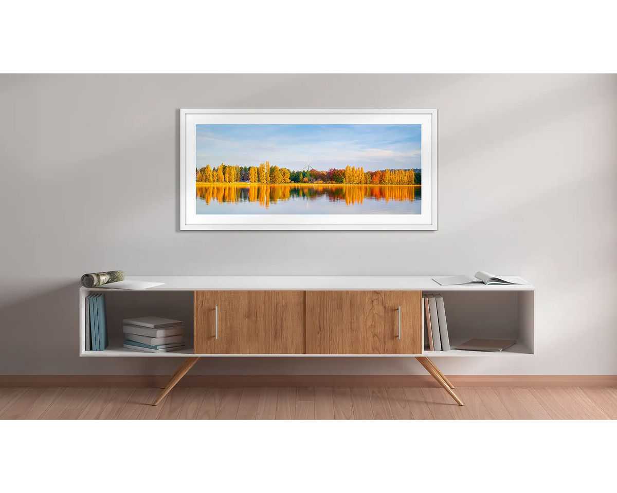 Changing Seasons. Wall art print with a white frame, of an autumn sunset, beside lake Burley Griffin, Canberra, hung above a side table. 
