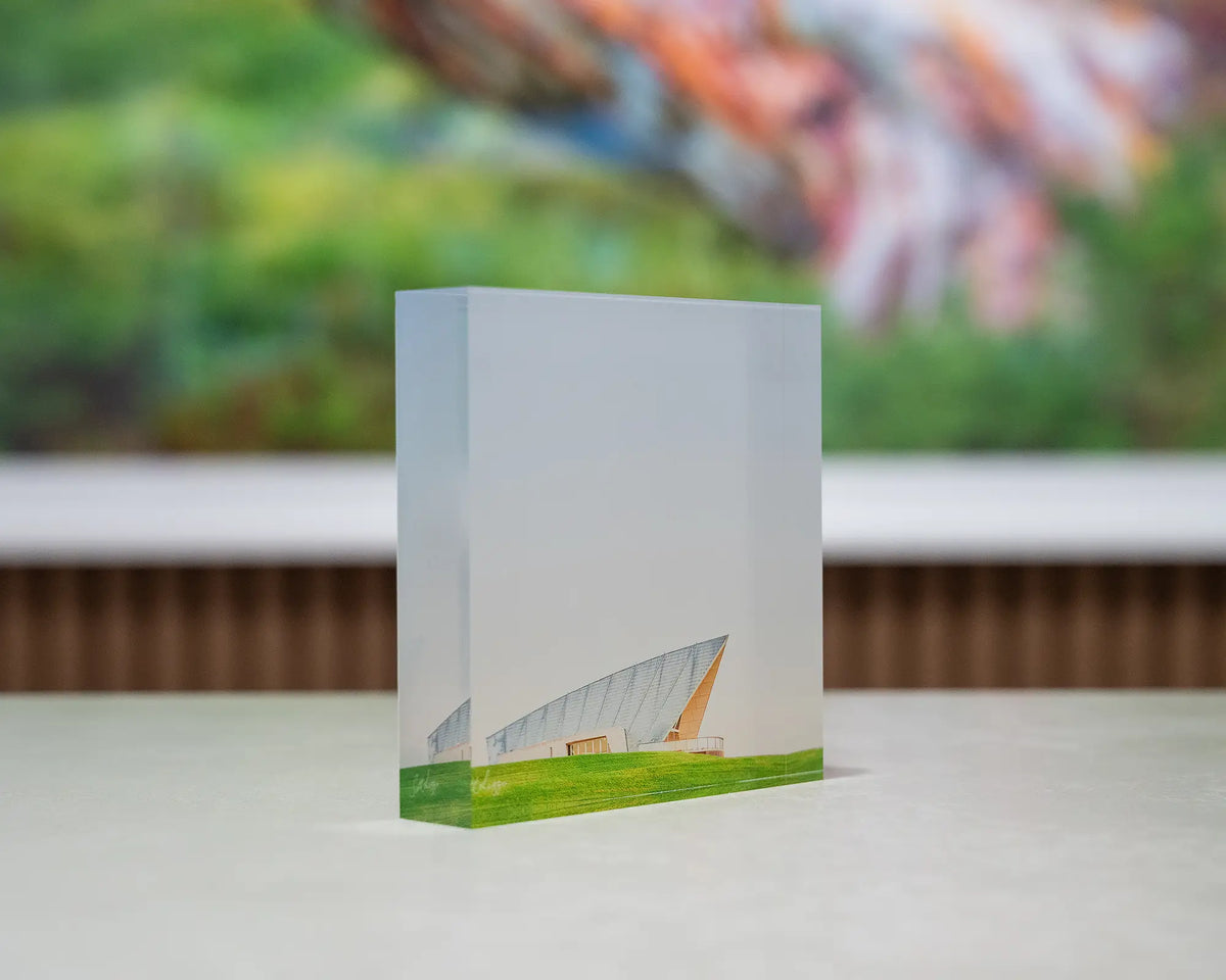 Clarity. Acrylic block Margaret Whitlam Pavilion, National Arboretum, Canberra, on desk with large Australian artwork in background.