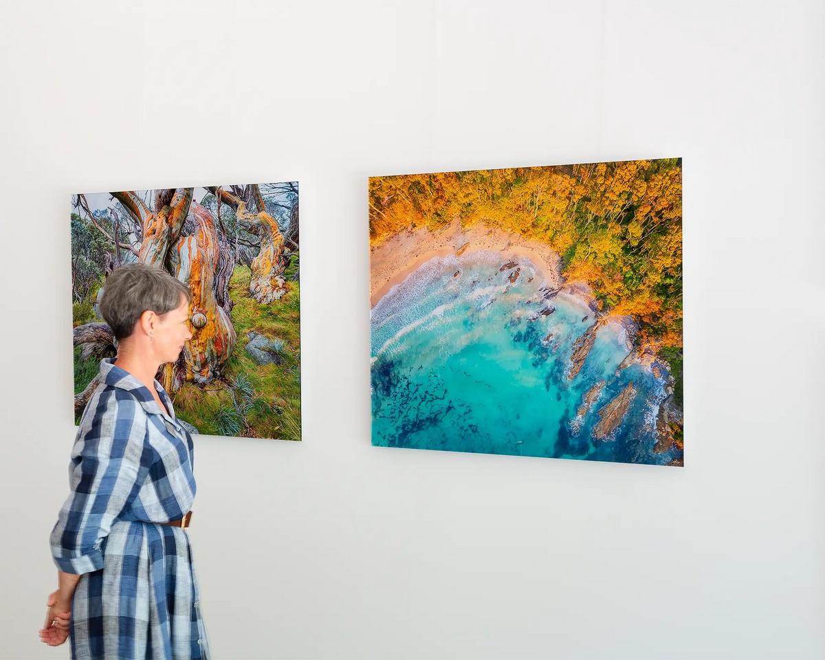 Coastal Bliss - Coastal beach wall art framless acrylic hanging on gallery wall with person admiring the artwork.