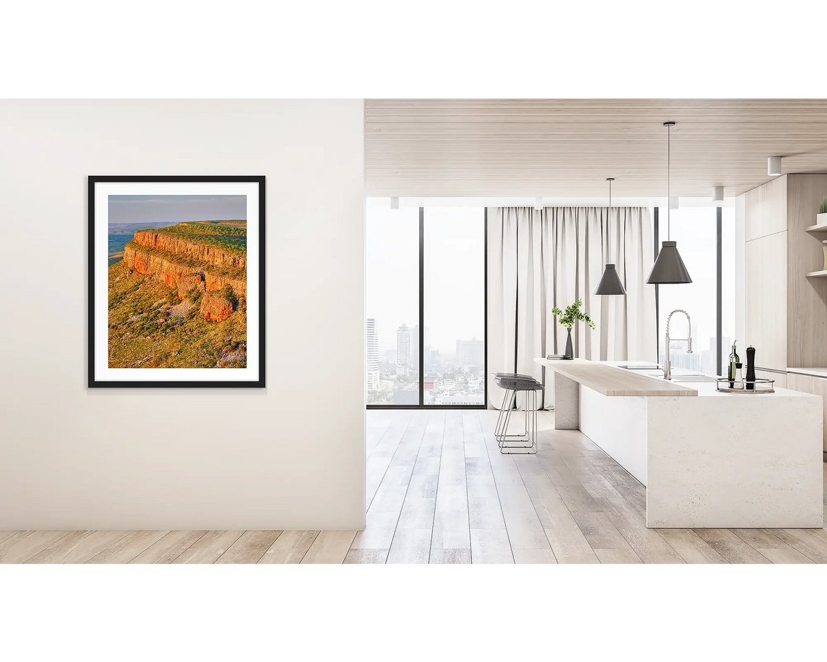 Collapse. Wall art print of Cockburn Ranges at sunset, with a black frame, hung on a hallway wall. 