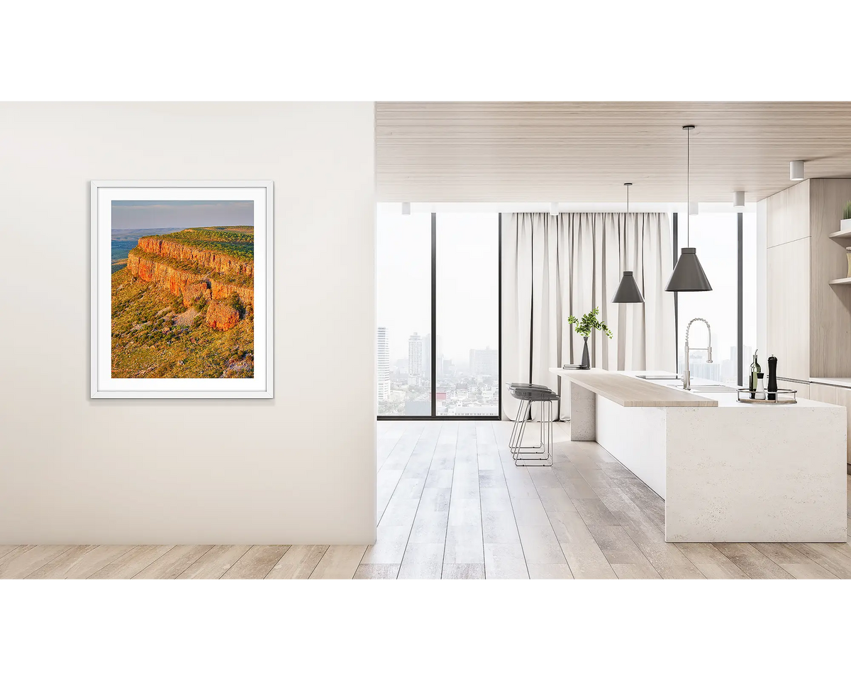 Collapse. Wall art print of Cockburn Ranges at sunset, with a white frame, hung on a hallway wall. 