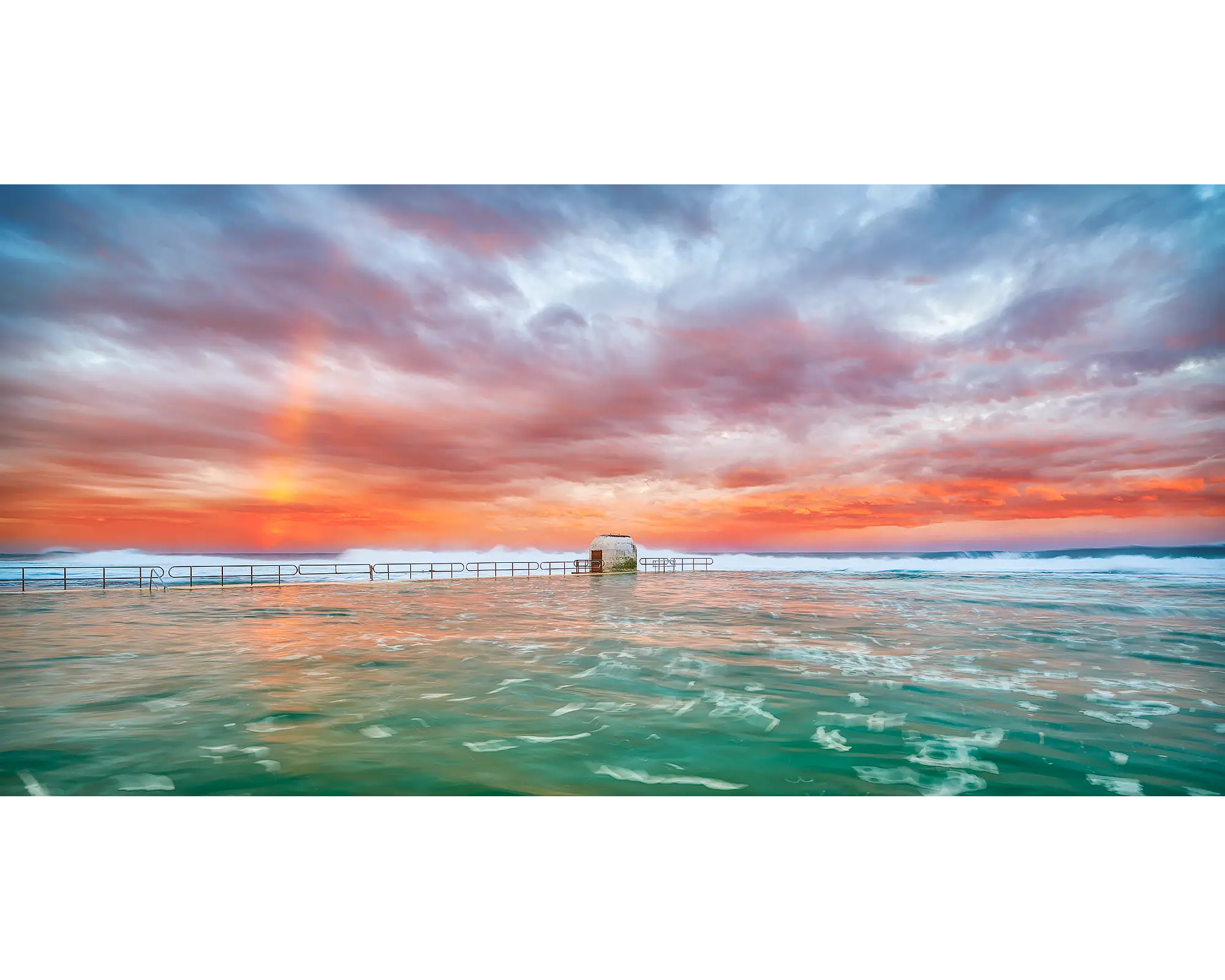 A rainbow and colourful clouds over Merewether Ocean Baths, Newcastle, NSW.