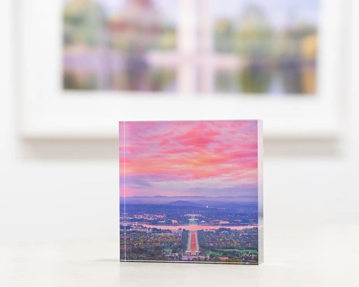 Colours Of Canberra. Acrylic block of sunrise over Canberra, on gallery desk with Canberra wall art in background.