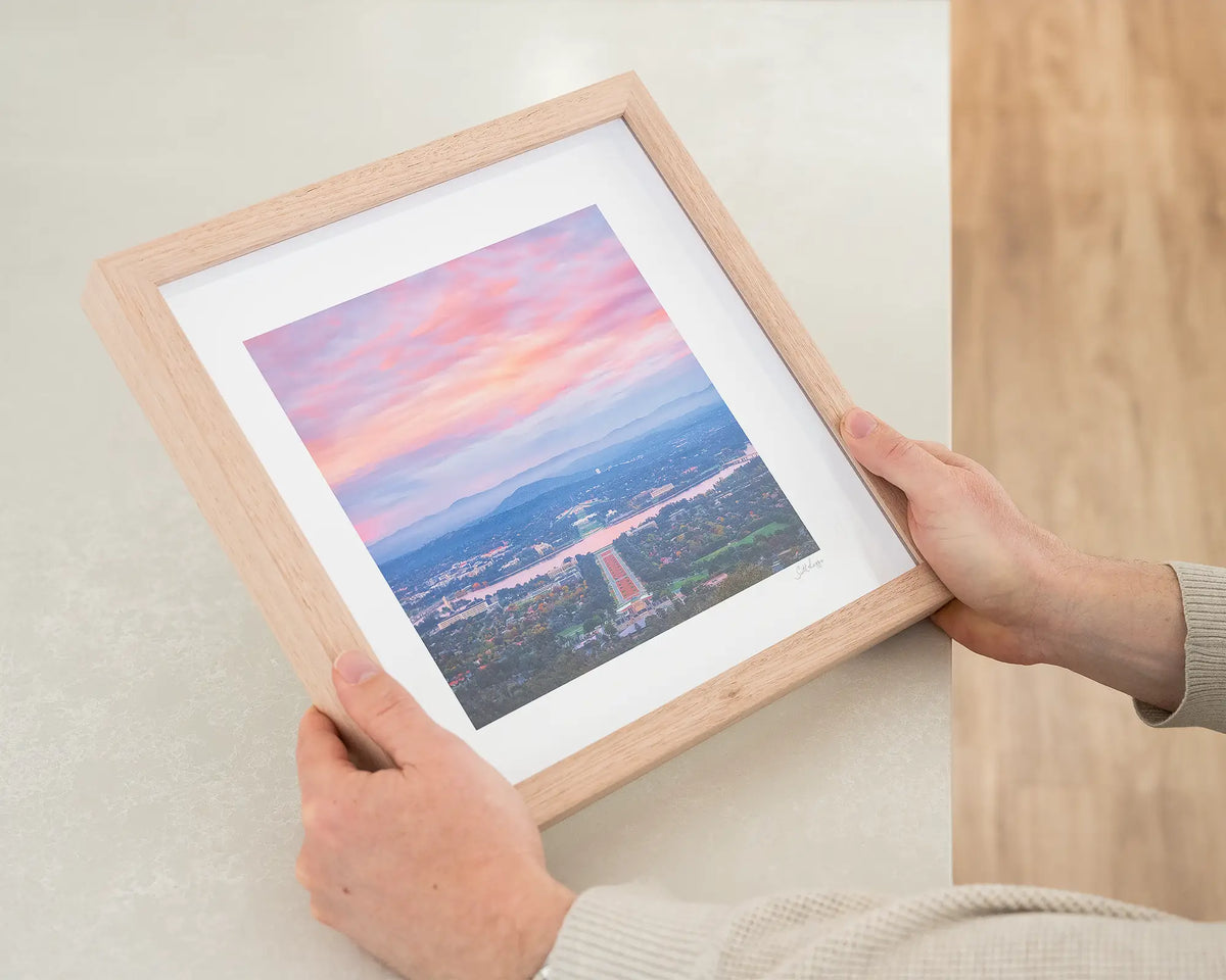 Colours of Canberra. Anzac parade at sunrise small print with a timber frame held in hands.