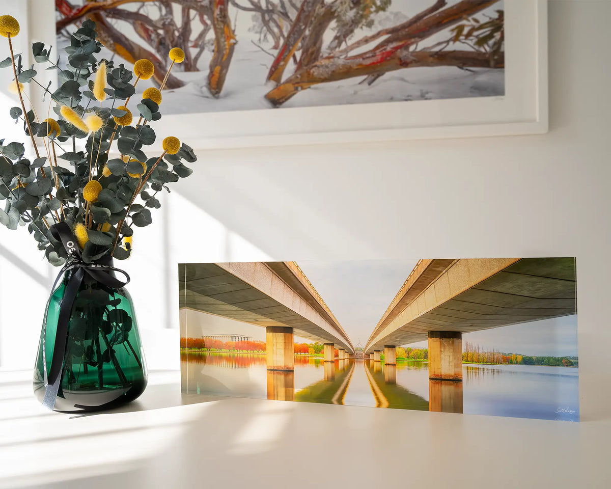 Convergent. Acrylic block of Commonwealth Avenue Bridge Canberra, sitting on a desk with flowers.