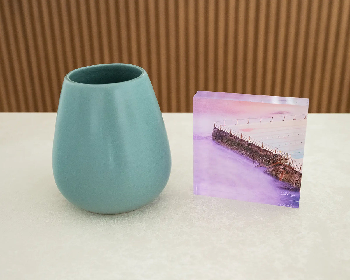 Corner. Acrylic block of Bondi Icerbergs, New South Wales, on desk styled with a small vase.