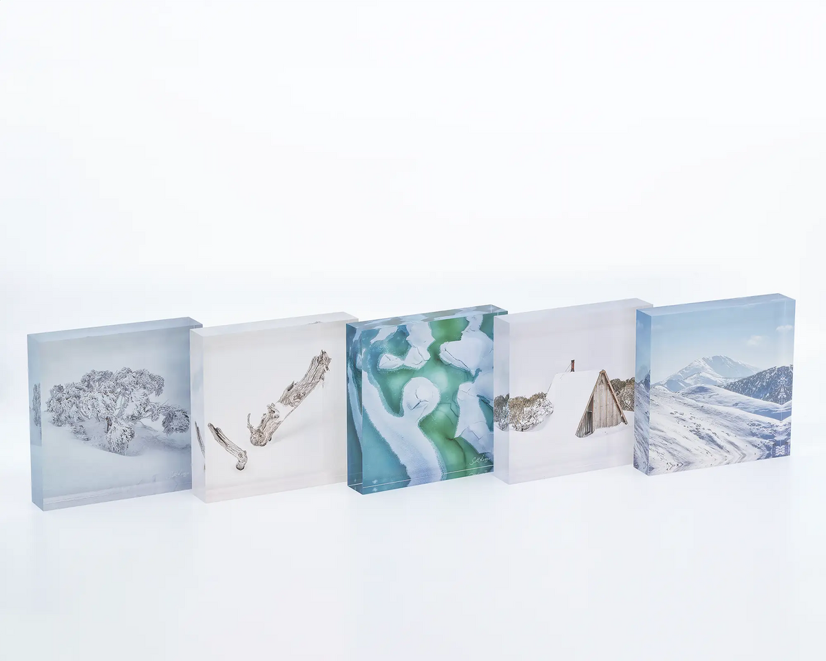 Cracked acrylic block sitting on a desk next to other snow themed artworks. 