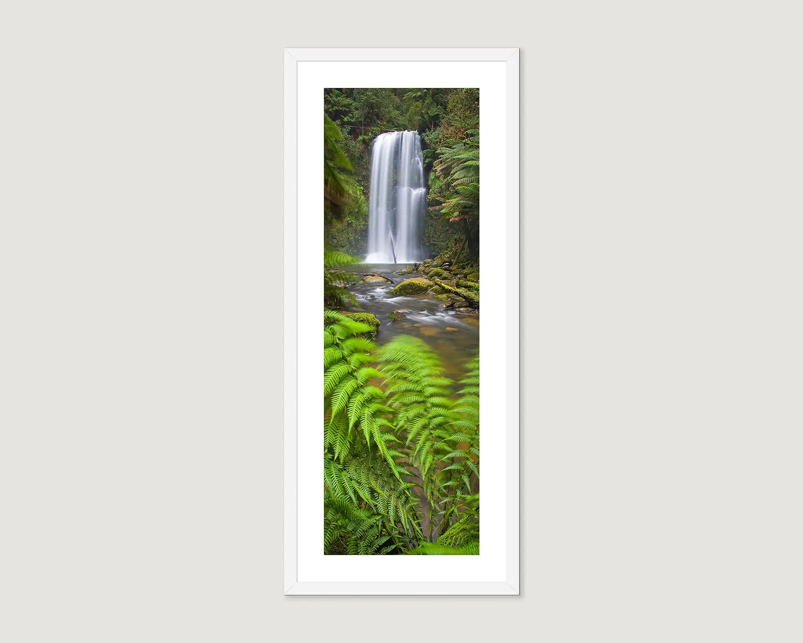 Framed photograph of a waterfall in a forest on a light gray background.
