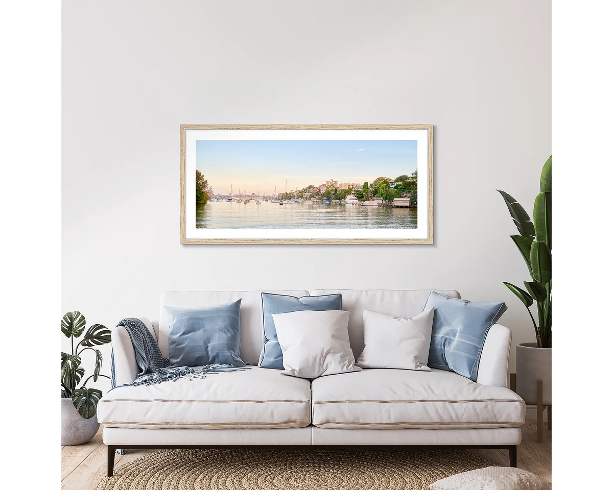 Cremorne Calm. Framed wall art print of Shell Cove, Sydney, with a timber frame, hung above a couch. 