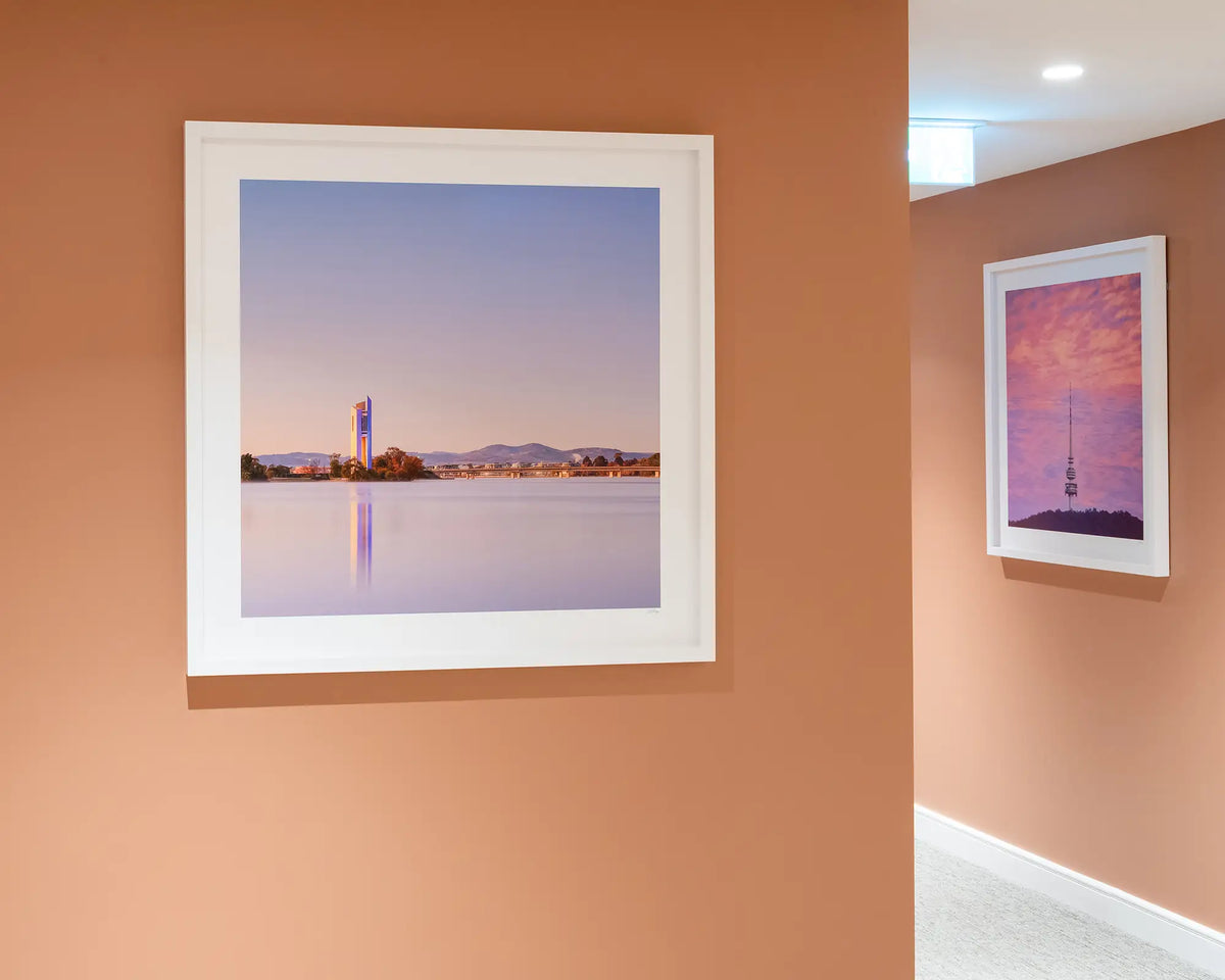 Crisp. Sunrise over National Carillon Canberra, with white frame hung on terracotta coloured wall with Pointer artwork around corner.