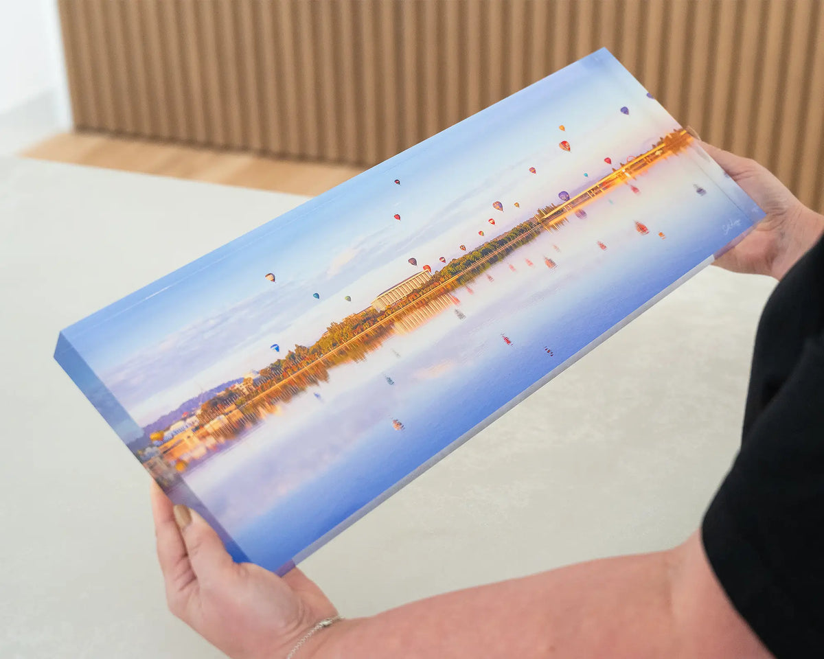 Dawn Drifters. Acrylic block of the Balloon Spectacular, Lake Burley Griffin Canberra, being held in hands.