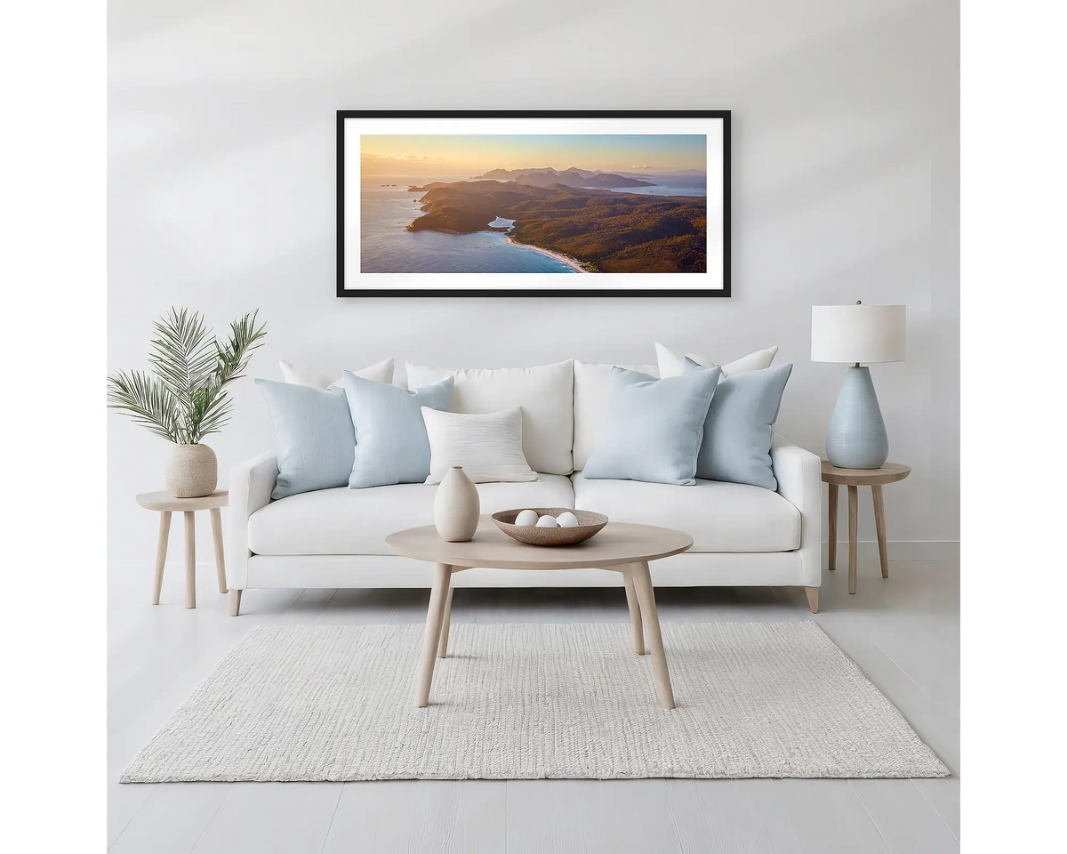 Dawn Over Freycinet. Framed wall art print of a sunrise over Freycinet National Park, with a black frame hung above a neutral coloured couch. 