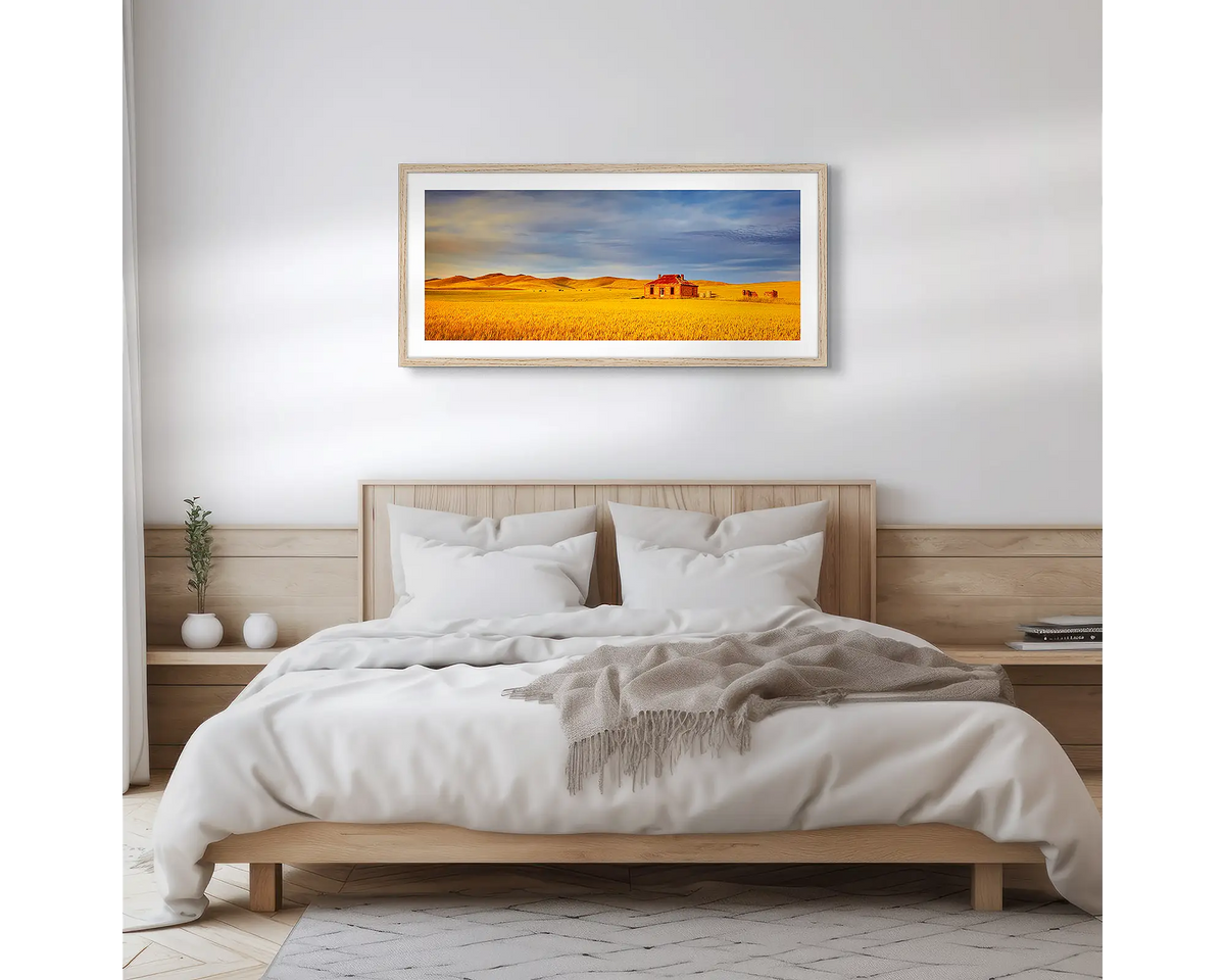 Days Gone By. Wall art print of a sunset over a wheat field and an old farm house, with a timber frame hung above a bed. 
