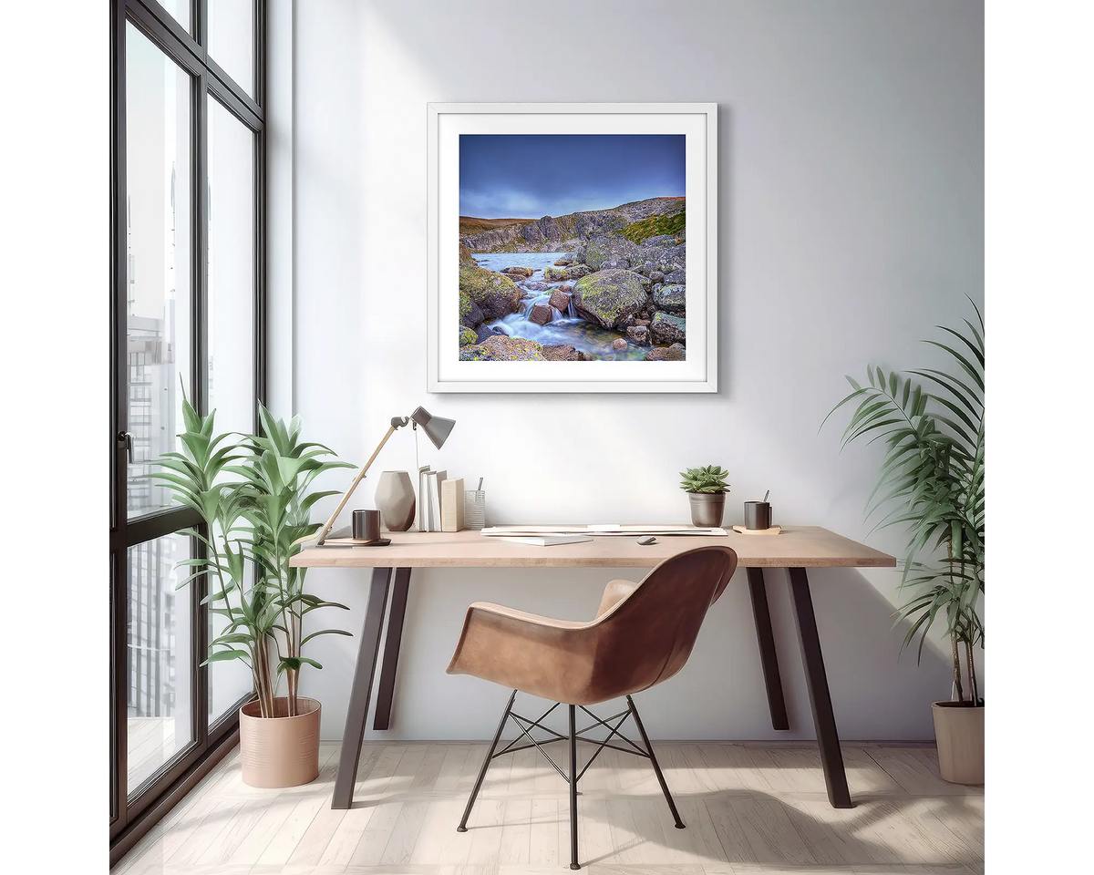 Deep Blue. Wall art print of Blue Lake in Kosciuszko National Park, with a white frame, hung above a desk in an apartment.
