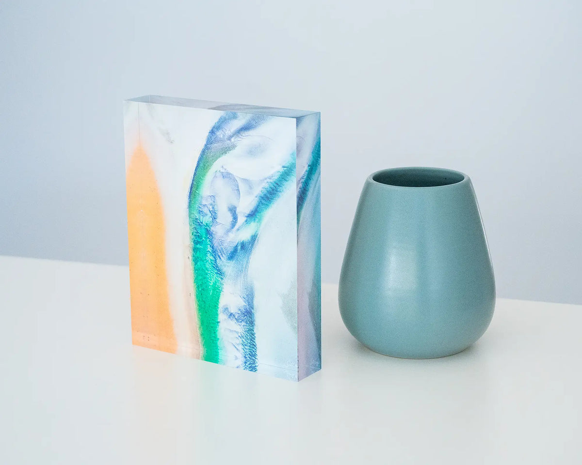Displacement. Acrylic block of the Kimberley aerial artwork, styled on a desk with a small vase.