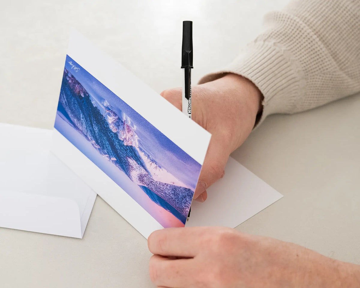 Distance greeting card of sunrise over Victorian alps, being written in with black pen.