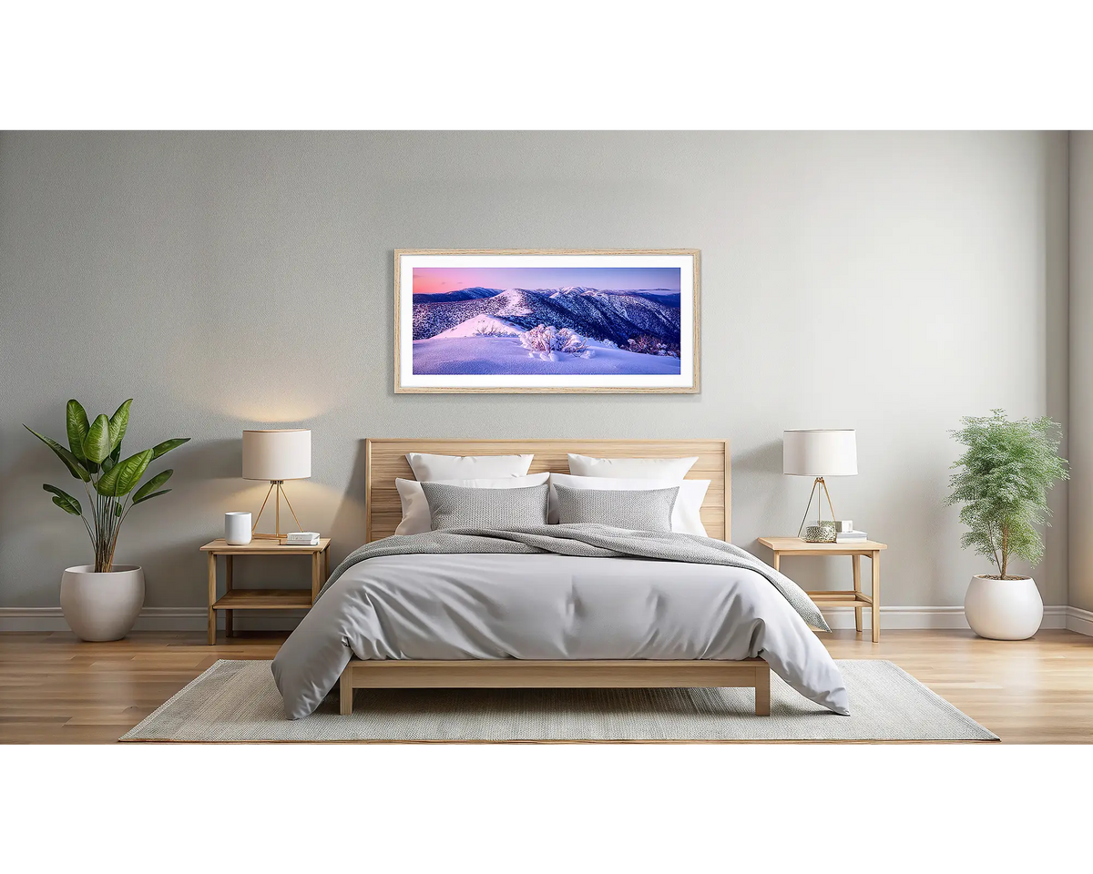 Distance. Wall art print with a Tasmanian Oak frame, of Mount Hotham with winter snow, hung in a light filled bedroom. 