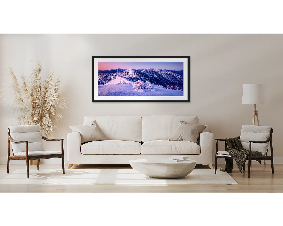 Distance. Winter alpine wall art in a black frame, above a couch. 