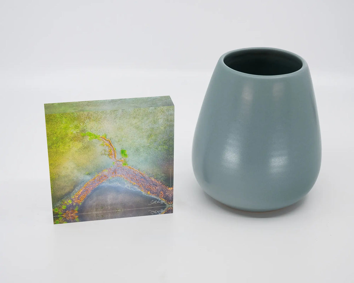 Divergent. Acrylic block of an aerial abstract view of Lake George, New South Wales, styled with a small vase.