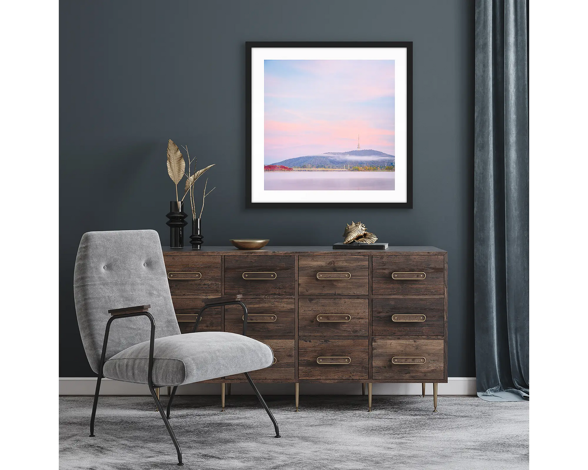 Dreamy Canberra. Framed wall art print of a sunrise over Canberra, with a black frame and hung above a side table.