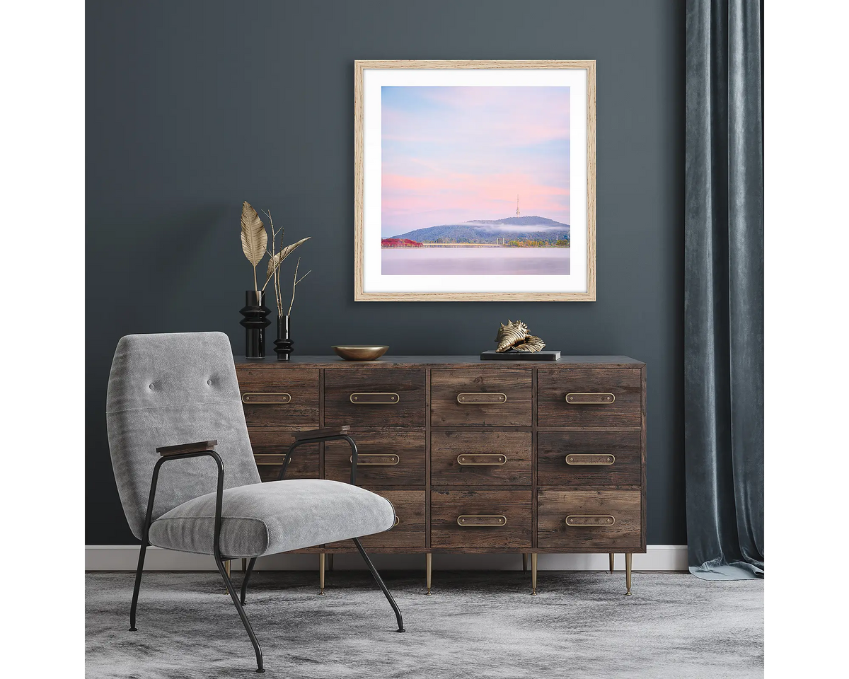 Dreamy Canberra. Framed wall art print of a sunrise over Canberra, with a timber frame and hung above a side table.
