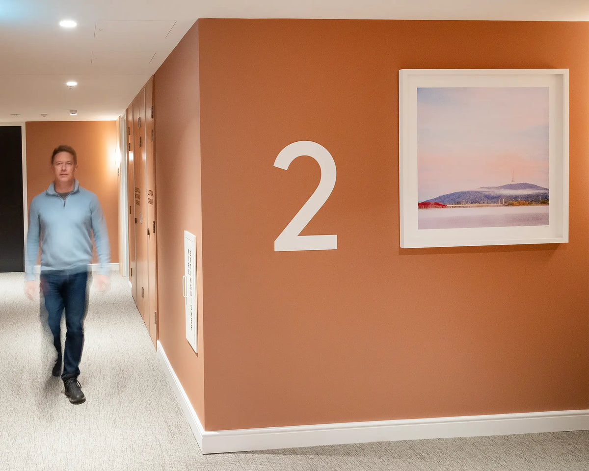 Dreamy Canberra. Sunrise with fog over Lake Burley Griffin,hung on terracotta wall, second floor commercial space with person walking down corridor.