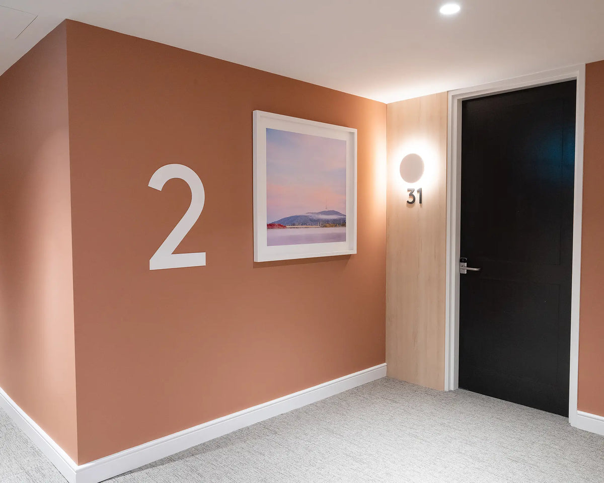 Dreamy Canberra. Sunrise with fog over Lake Burley Griffin, with white frame hung on terracotta coloured wall, second floor apartment building.