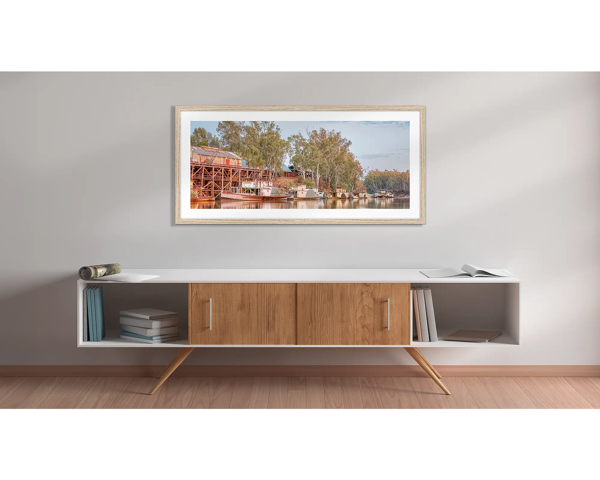 Echuca Lineup. Wall art print with a timber frame, of paddle steamers and Echuca wharf, hung above a side table. 