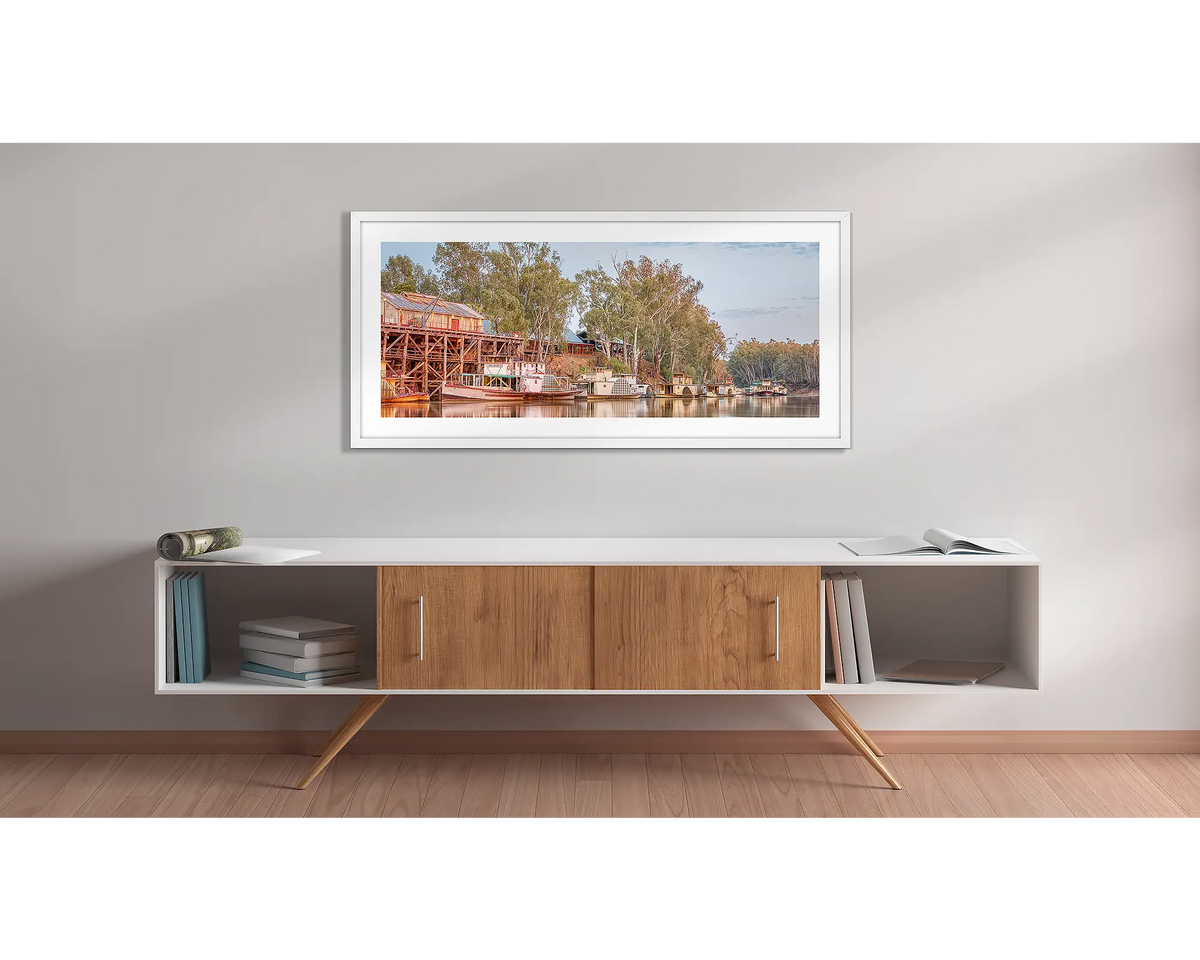 Echuca Lineup. Wall art print with a white frame, of paddle steamers and Echuca wharf, hung above a side table. 