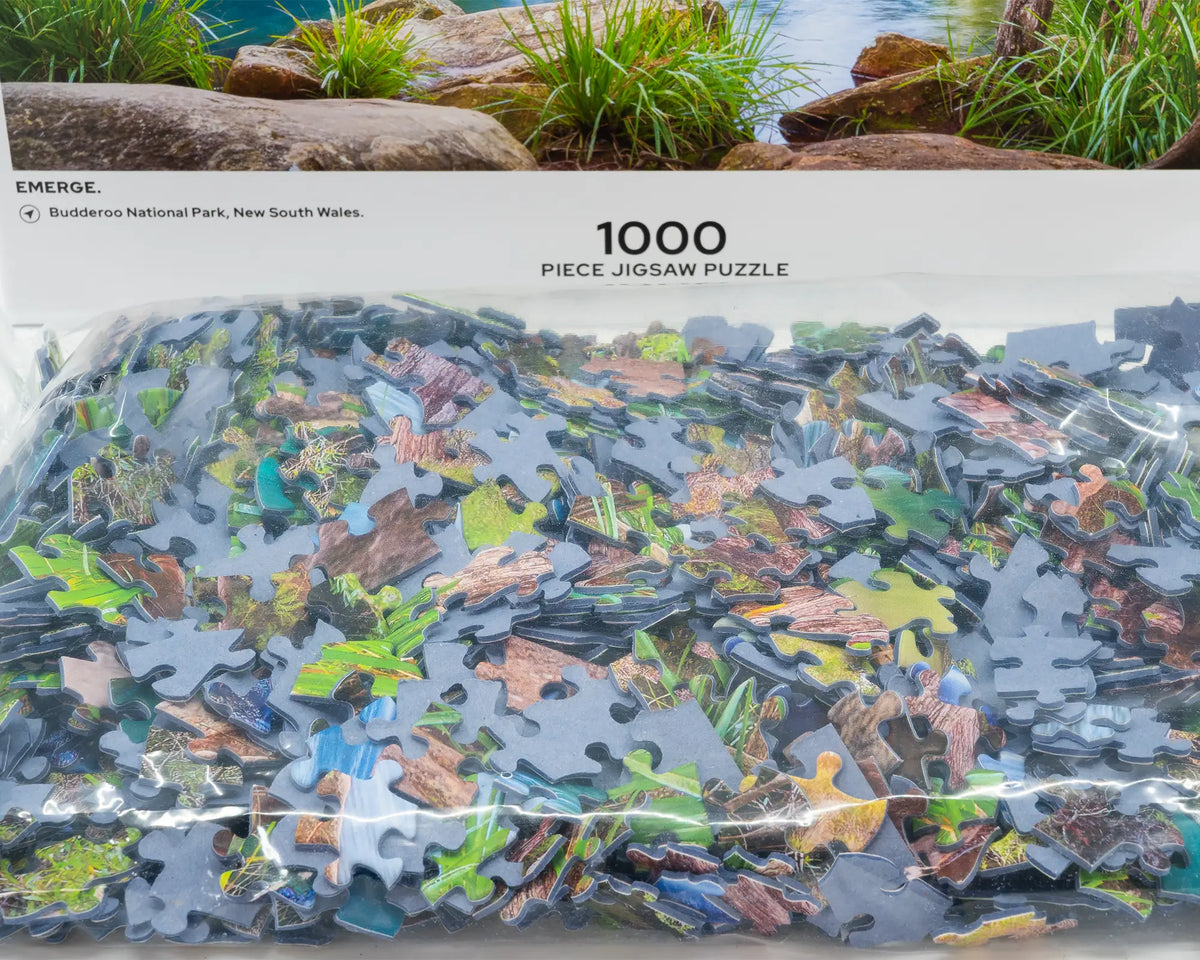 Emerge. 1000 piece jigsaw puzzle open box showing unique cut puzzle pieces, Buddaroo National Park, New South Wales.