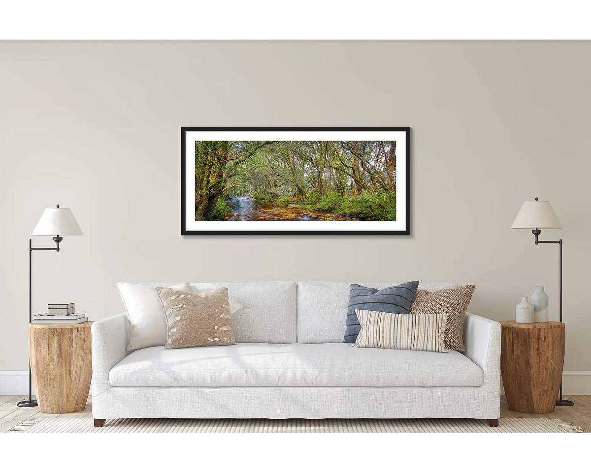 Enchanted. Panoramic Tasmanian wall art print with a black frame, hanging above a couch.