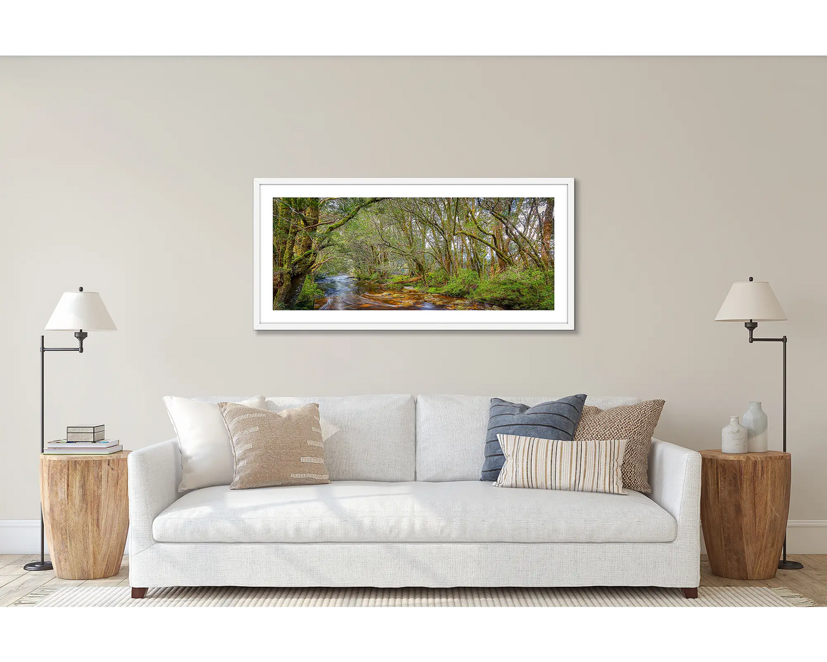 Enchanted. Panoramic Tasmanian wall art print with a white frame, hanging above a couch.