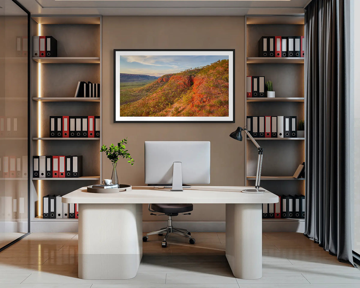 Enduring. Wall art print of Cockburn Range, the Kimberley, with a black frame, hanging behind a desk in a corporate office. 