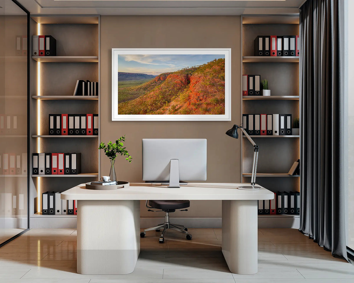 Enduring. Wall art print of Cockburn Range, the Kimberley, with a white frame, hanging behind a desk in a corporate office. 