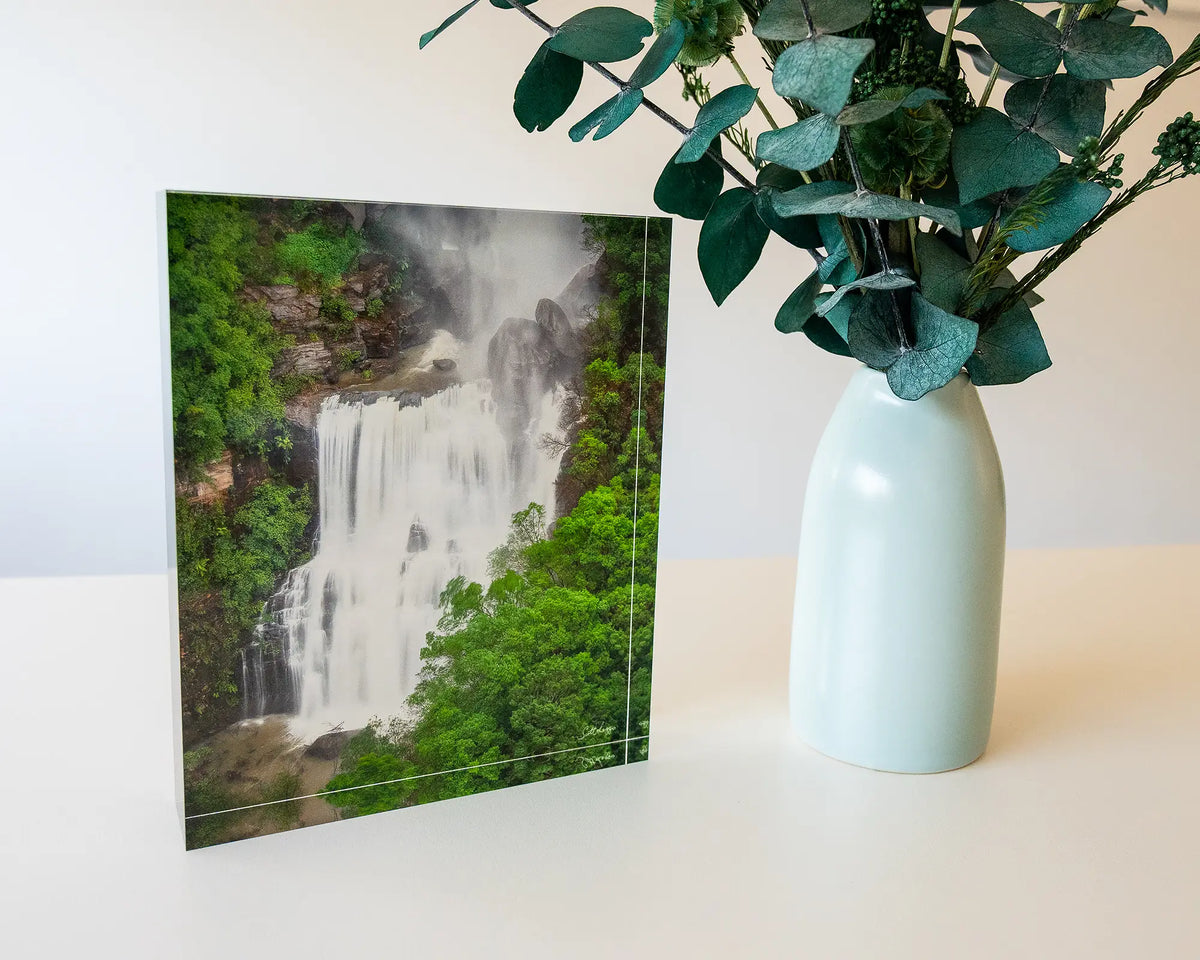 Energy. Acrylic block Fitzroy Falls, Morton National Park, on desk with small vase of flowers.