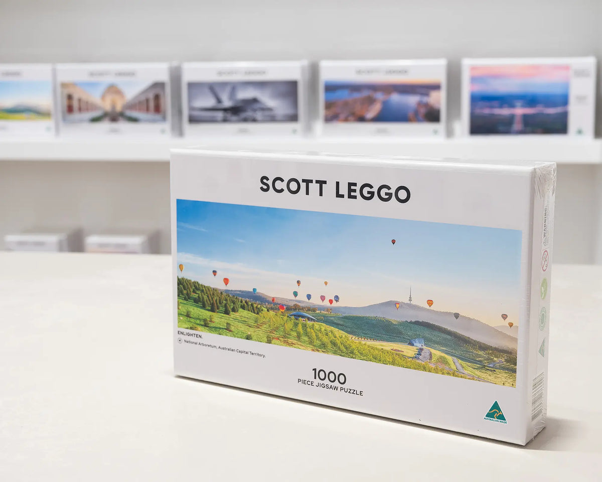 Enlighten 1000 piece jigsaw puzzle sitting on desk in front of other puzzles.