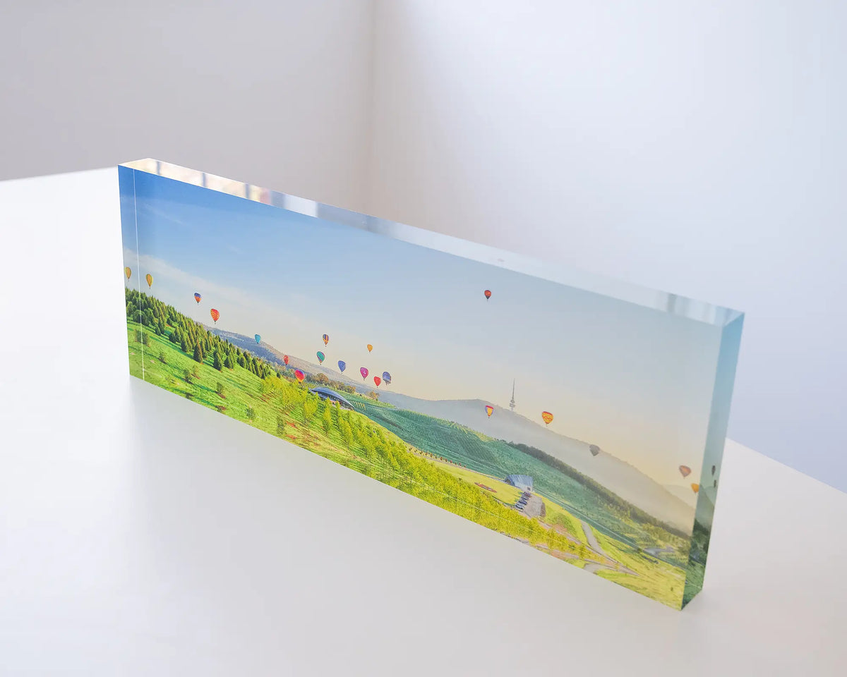 Enlighten. Acrylic block of hot air balloons over National Arboretum, Balloon Spectacular Festival, Canberra, on desk.