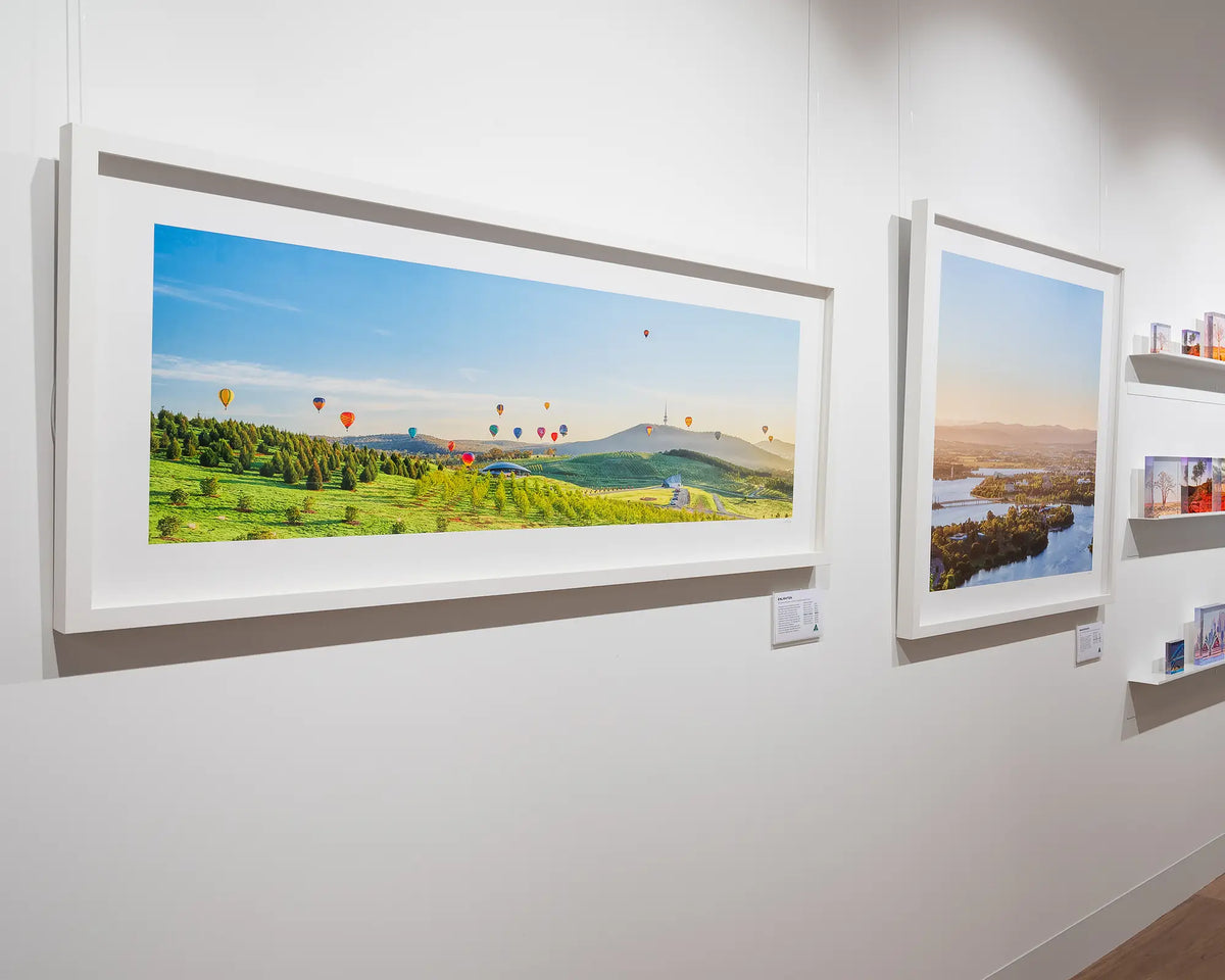 Enlighten. Canberra Balloon Spectacular over the National Arboretum, with white frame, in gallery with more Canberra artwork.