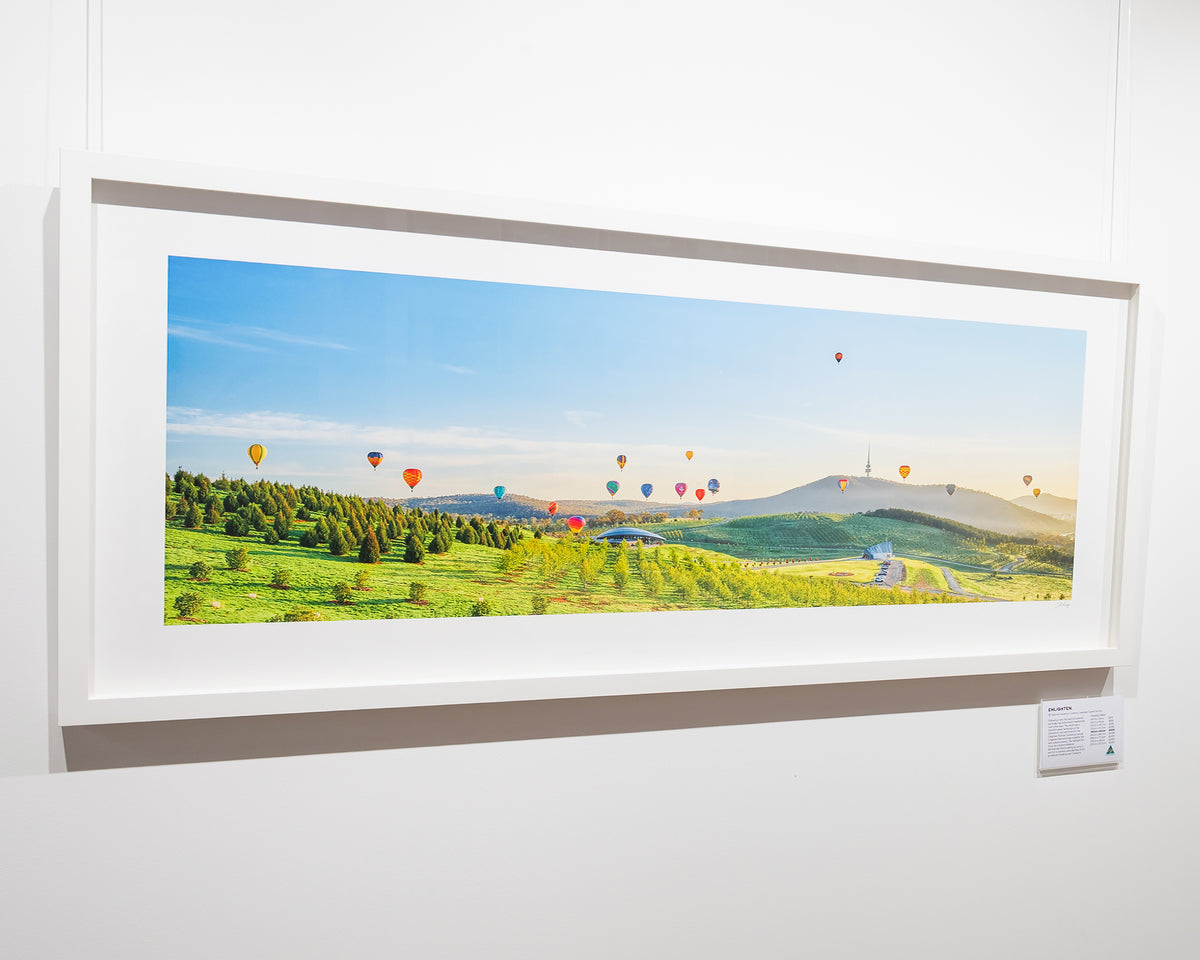 Enlighten. Canberra Balloon Spectacular over the National Arboretum, with white frame, hung in gallery.