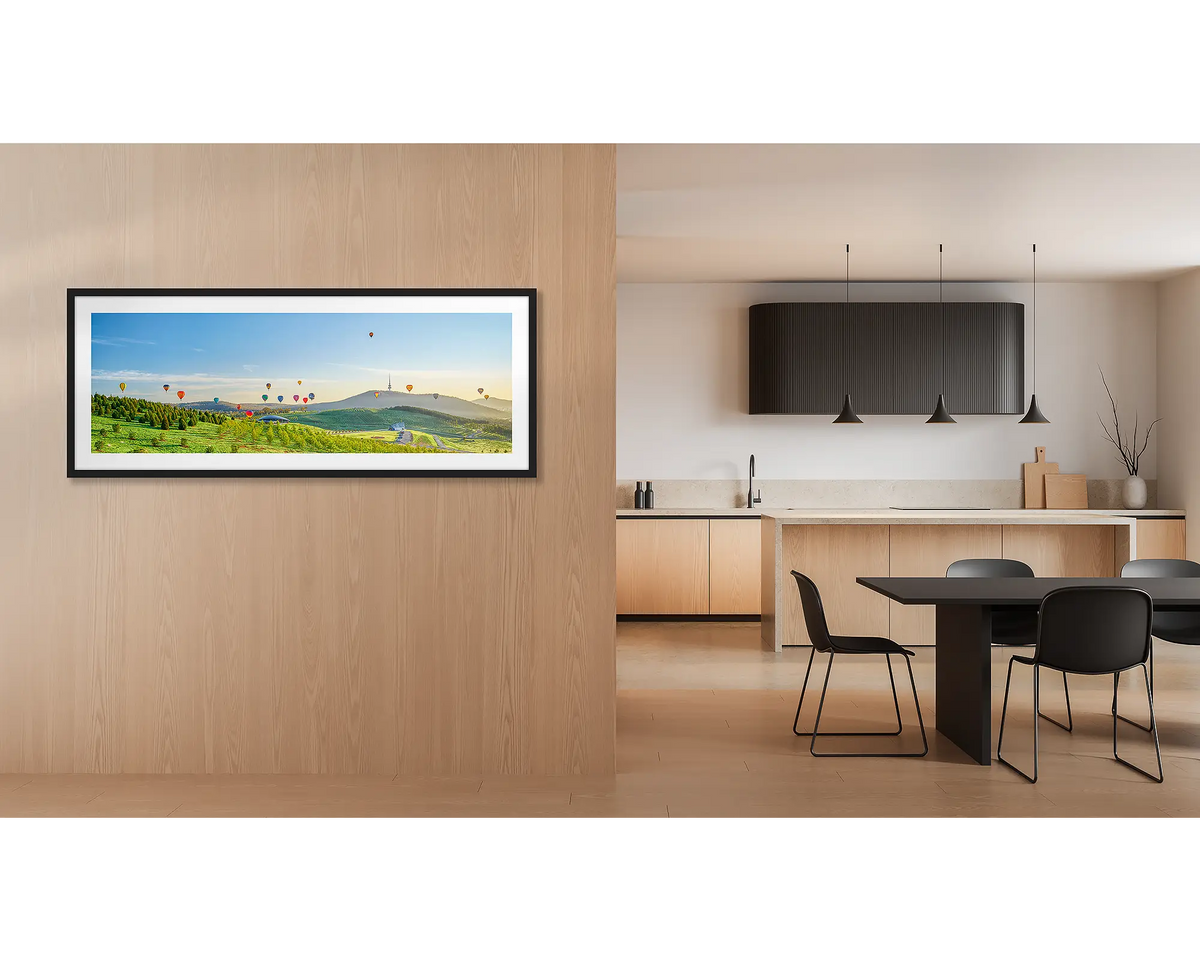 Enlighten. Wall art print of hot air balloons over the arboretum at sunrise, framed with a black frame and hung outside a kitchen. 