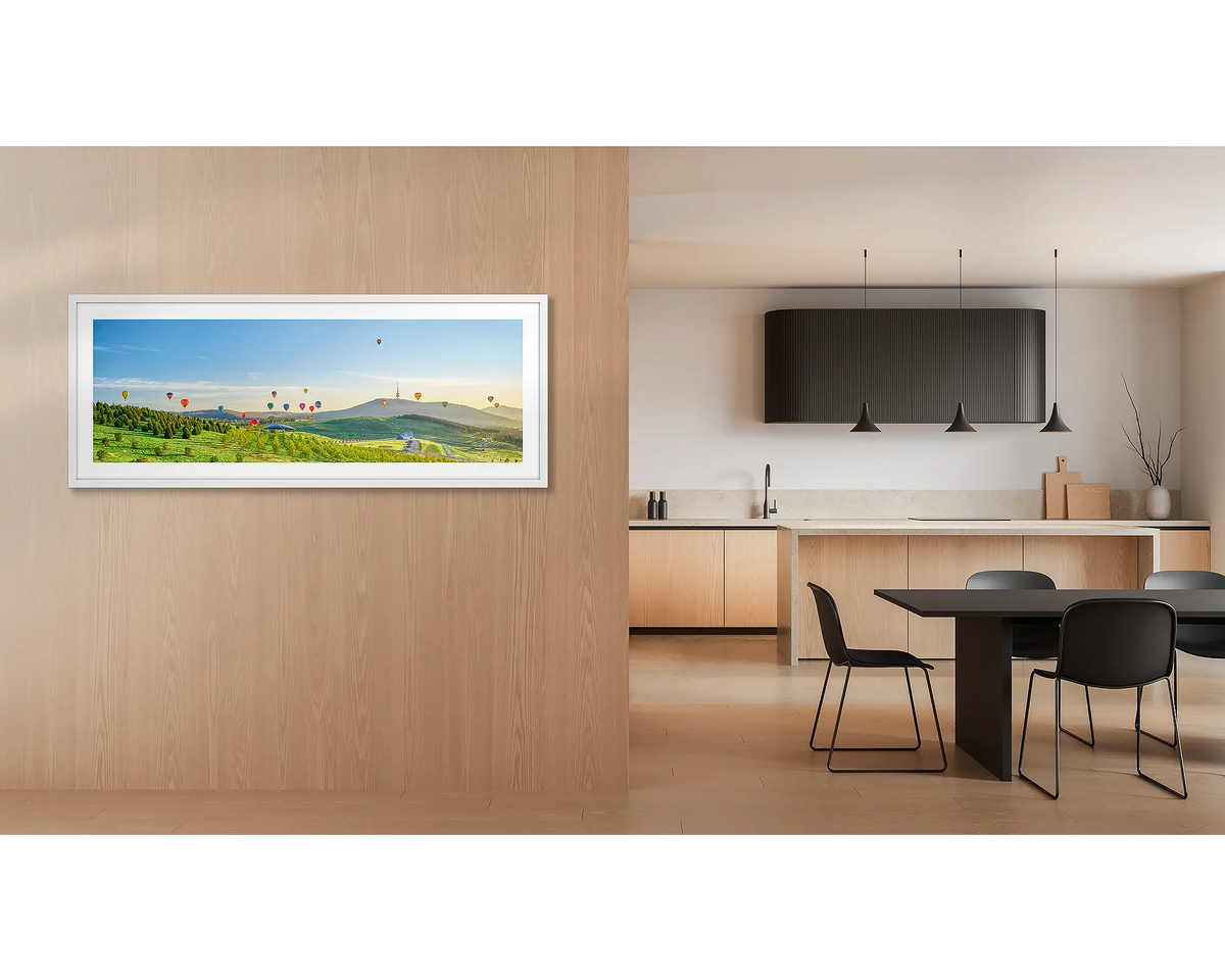 Enlighten. Wall art print of hot air balloons over the arboretum at sunrise, framed with a white frame and hung outside a kitchen. 