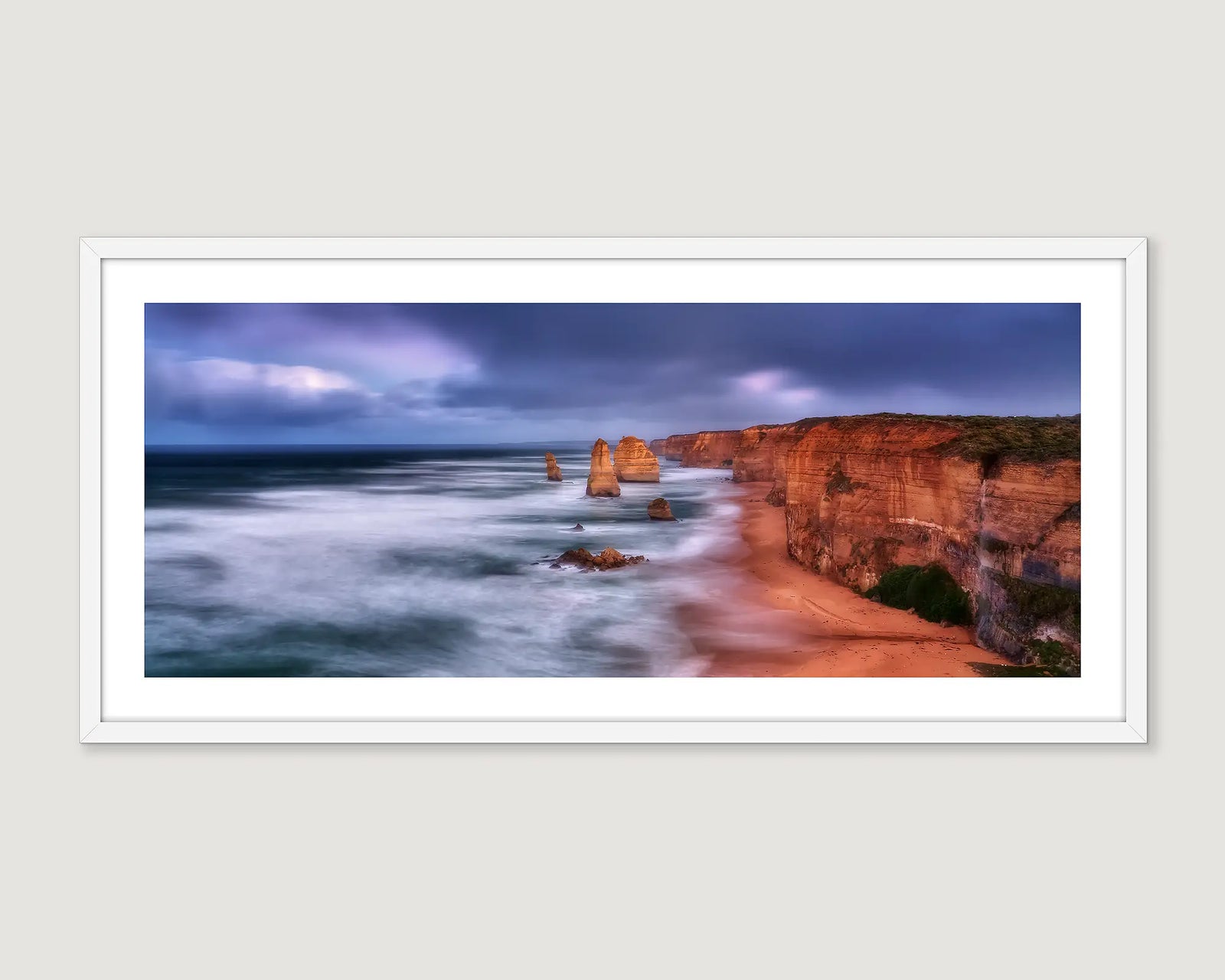 Framed photograph of a cliff, the ocean and the twelve apostles against a stormy sky.