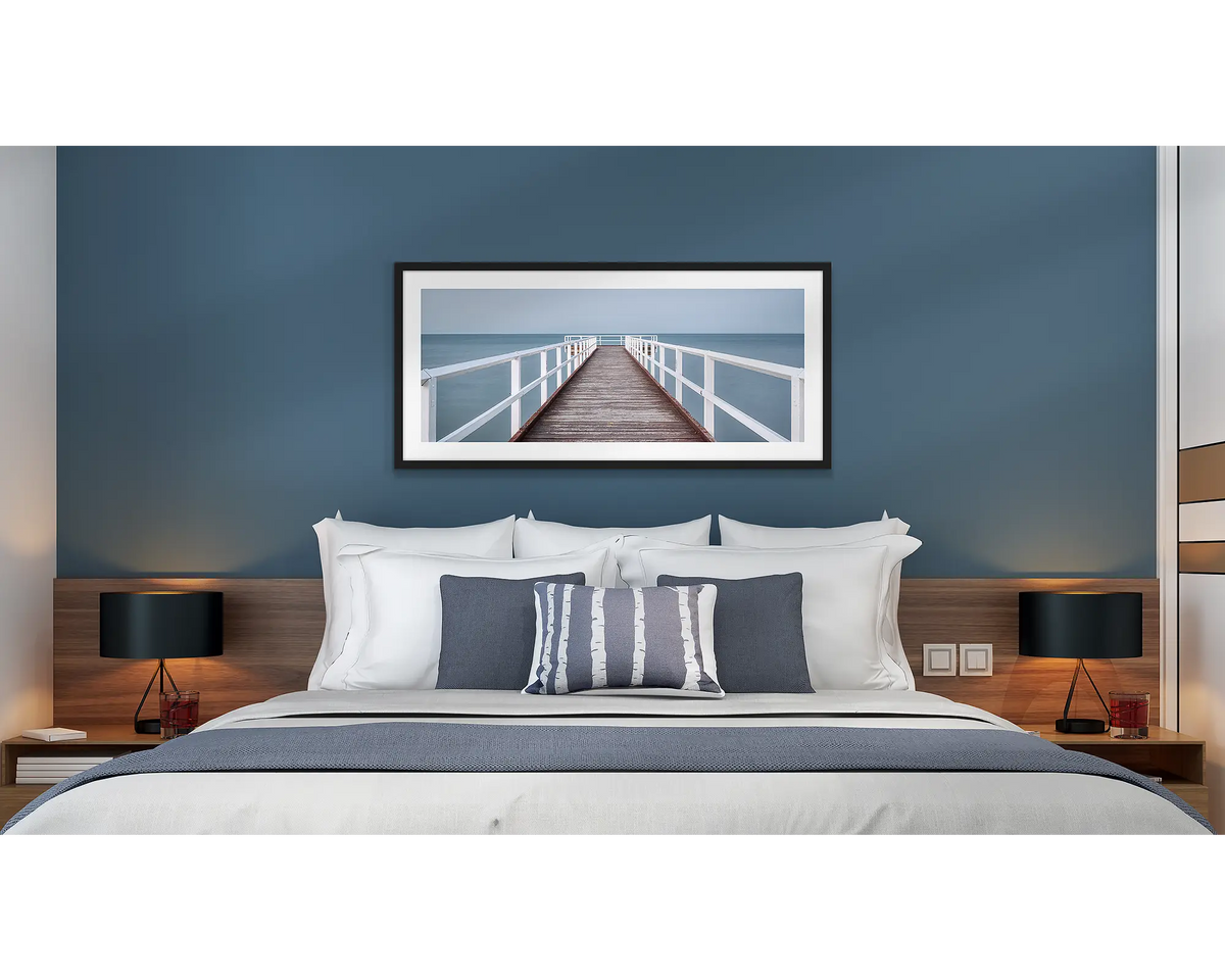 Evening Calm. Framed wall art print of a jetty with a black frame, hung above a bed in a hotel room. 