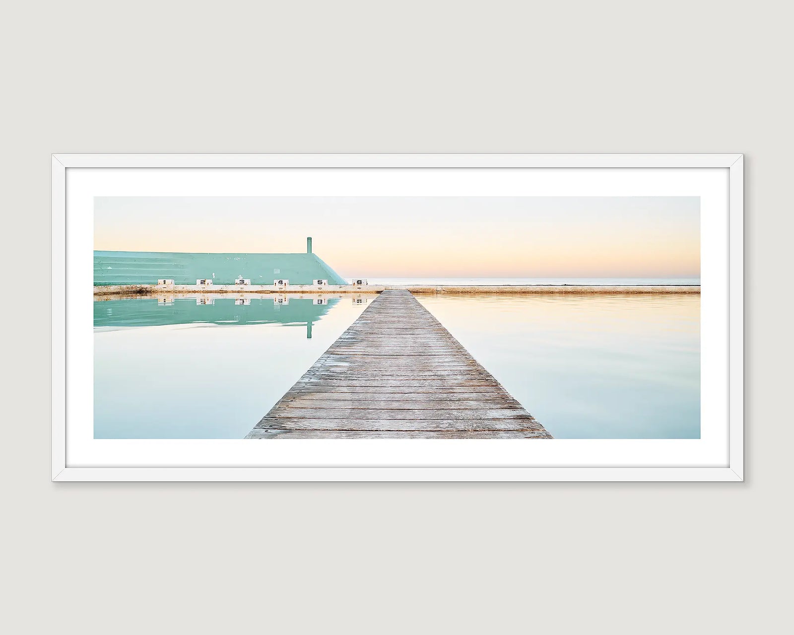 Framed photographic print of still water and a jetty at Newcastle Ocean Baths at sunrise.