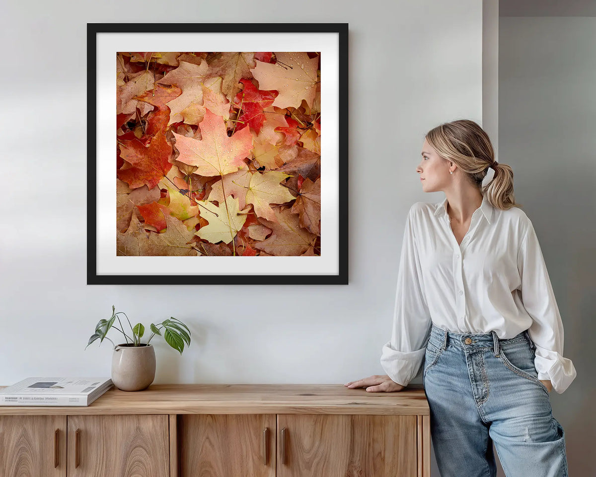 Fallen. Wall art print with black frame featuring autumn leaves in Bright Victoria, hung above a side table.
