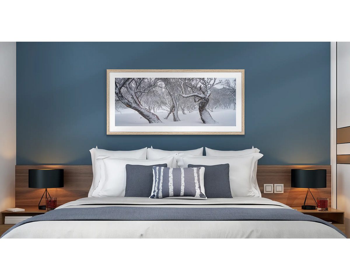 Family Twist. Old twisted snow gums in snow, wall art print in a timber frame hung above a bed in a hotel room. 
