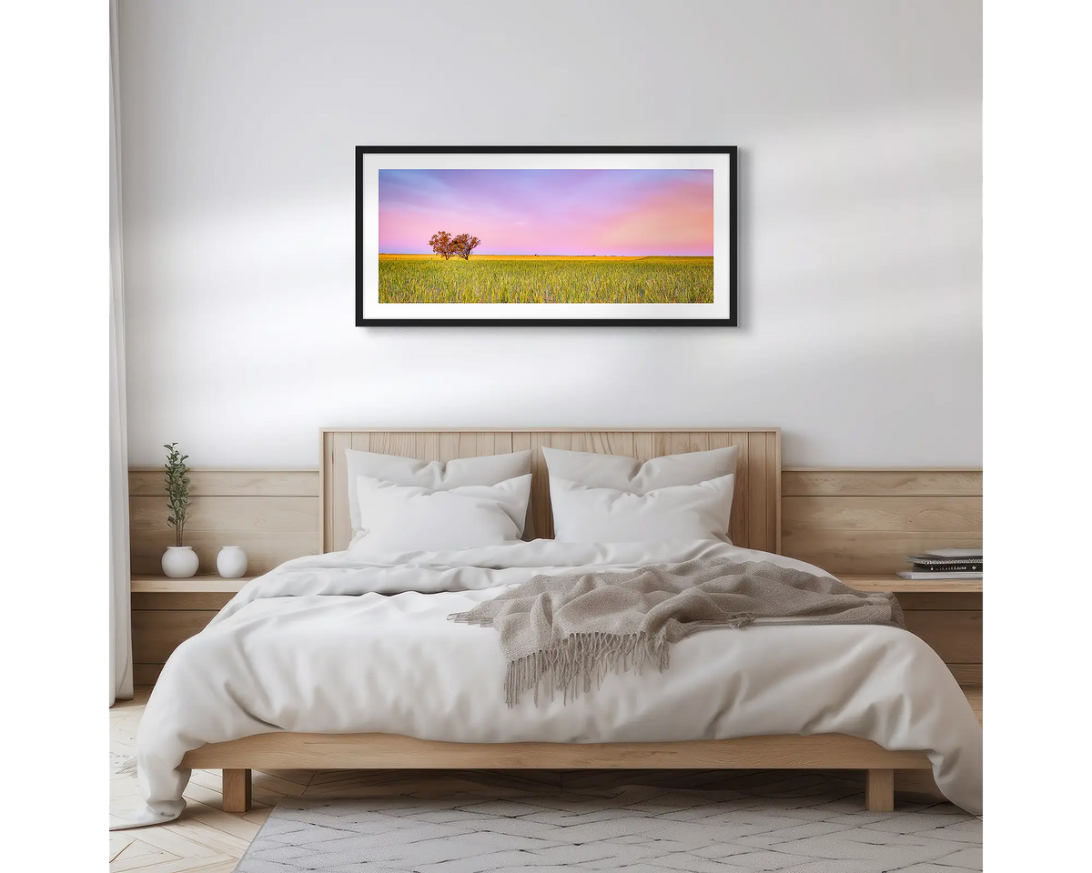 Farm Life. Framed wall art print of a sunset over a farm, with a black frame hung above a bed.