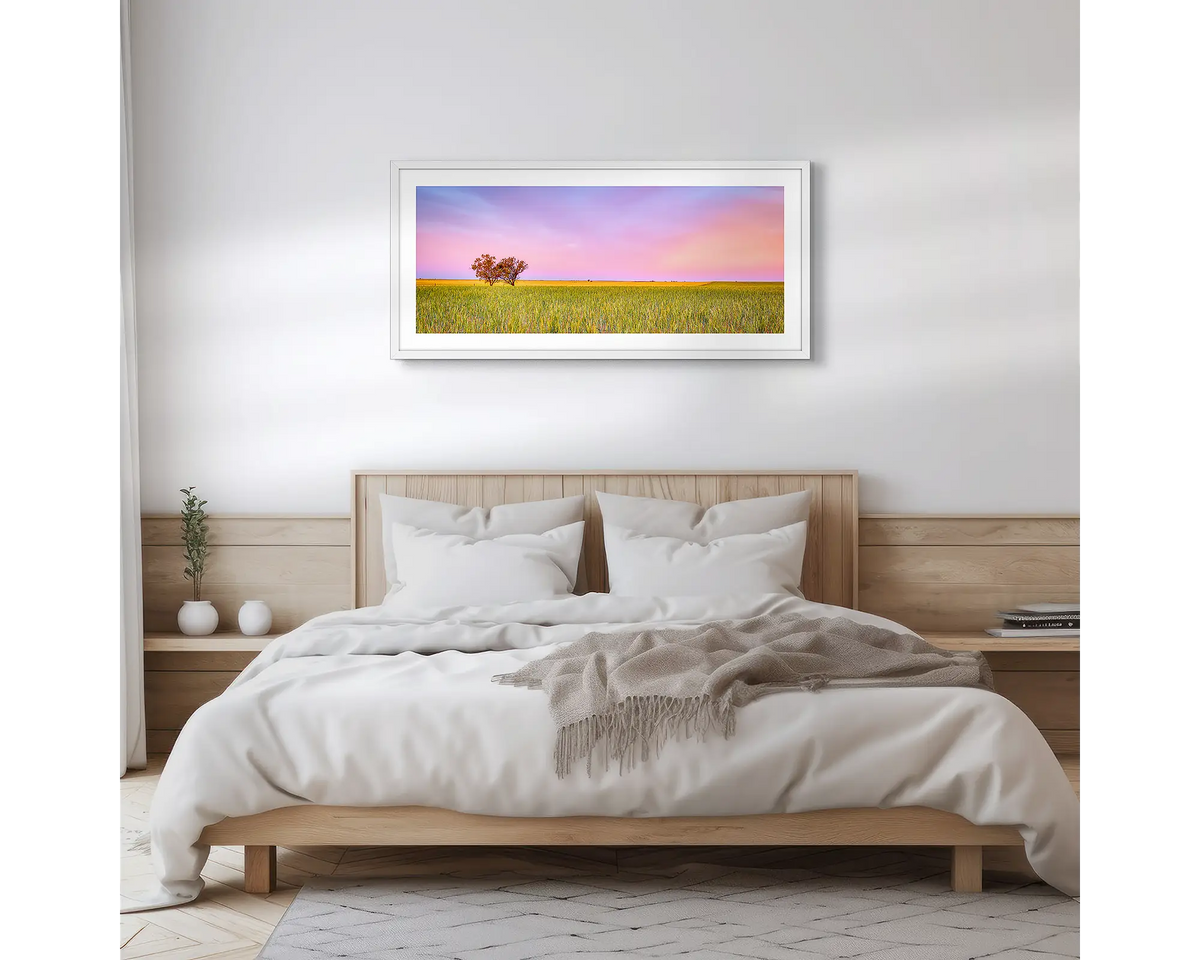Farm Life. Framed wall art print of a sunset over a farm, with a white frame hung above a bed.