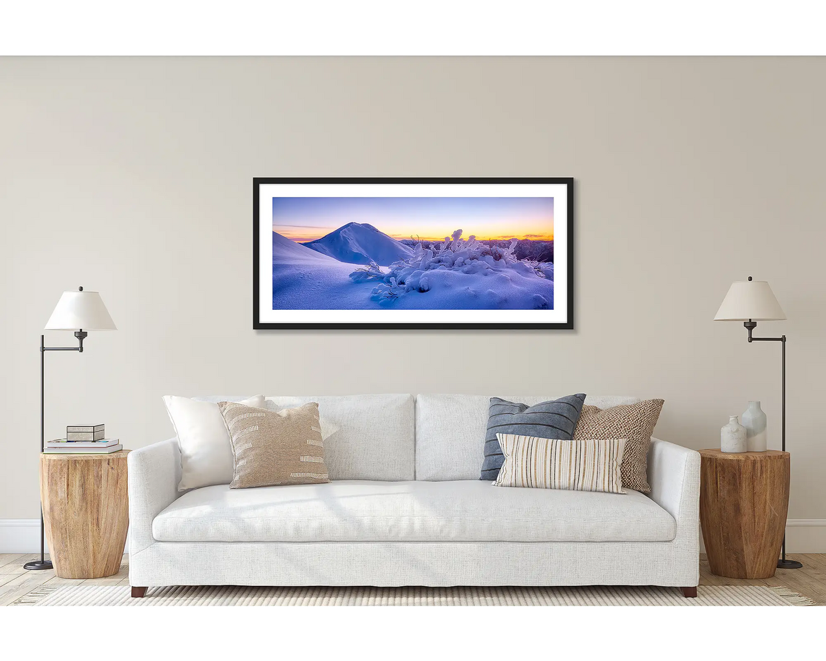Feathertop Dawn. Wall art print of a winter sunrise over Mount Feathertop, framed with a black frame and hung above a couch. 